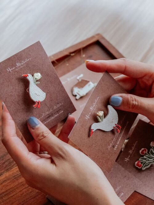 Woodland Story Embroidery Pins - Cubby Goose held in hand.|Woodland Story Embroidery Pin - Cubby Goose on card with golden pin|Woodland Story Embroidery Pins featuring a goose design, held in hand.