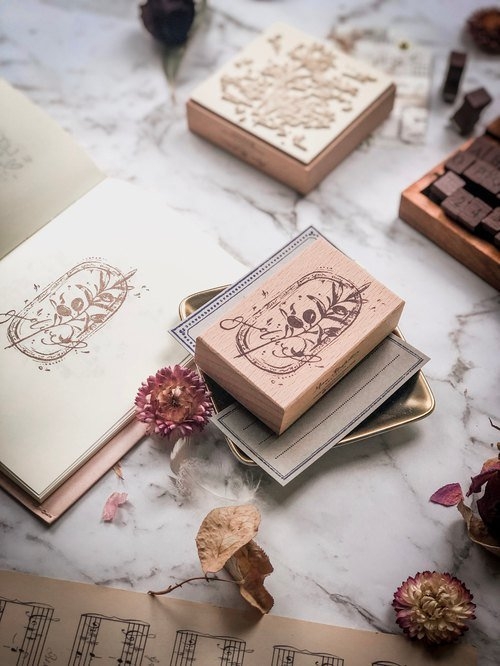 Botanic Stamp in olive green on marble surface with floral design.