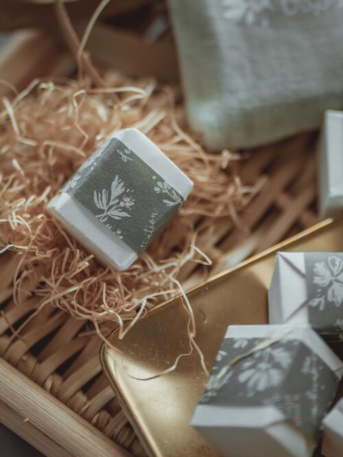 Oopsy Daisy wooden stamp in mystery packaging on wicker tray.