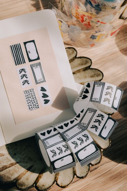 PaperNote black sticker label roll with various designs on a table.