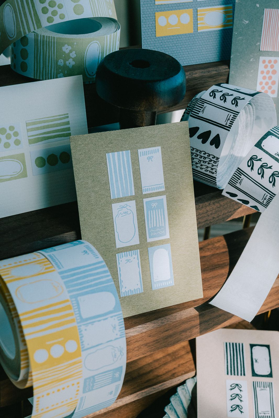 PaperNote Sticker Label Roll in blue with various designs on a wooden shelf.